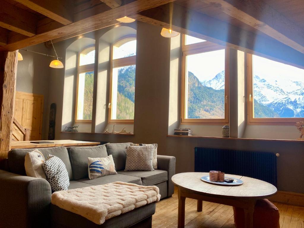 a living room with a couch and a table and windows at Ancienne école du Mont in Servoz