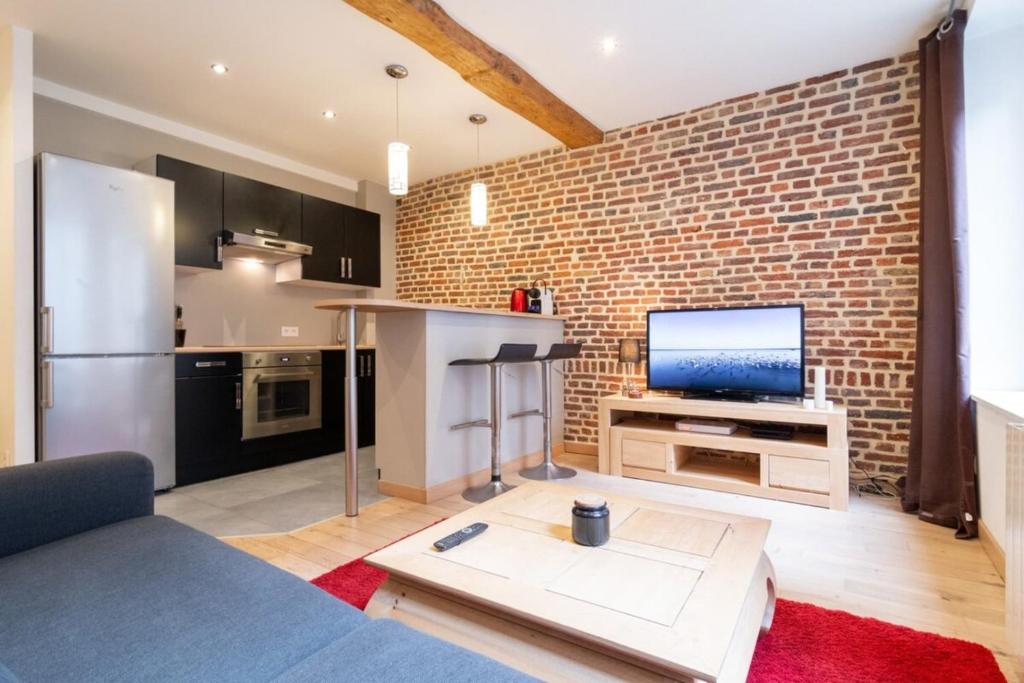 Il dispose d'une cuisine et d'un salon avec un mur en briques. dans l'établissement Vieux Lille - Appart lumineux avec cachet ! 2pers, à Lille