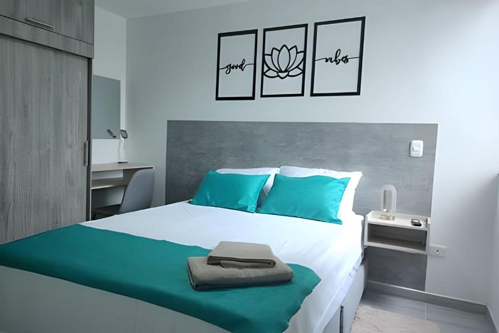 1 dormitorio con cama blanca y almohadas azules en GURUS FR | Elegante Apartamento en parque acuático Dosquebradas, en Dosquebradas
