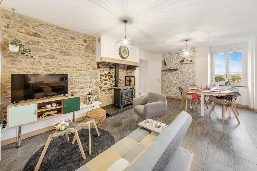 a living room with a stone wall and a dining room at Beauregard - Jolie maison - Vue sur Rance - 4 pers in Saint-Jouan-des-Guérets