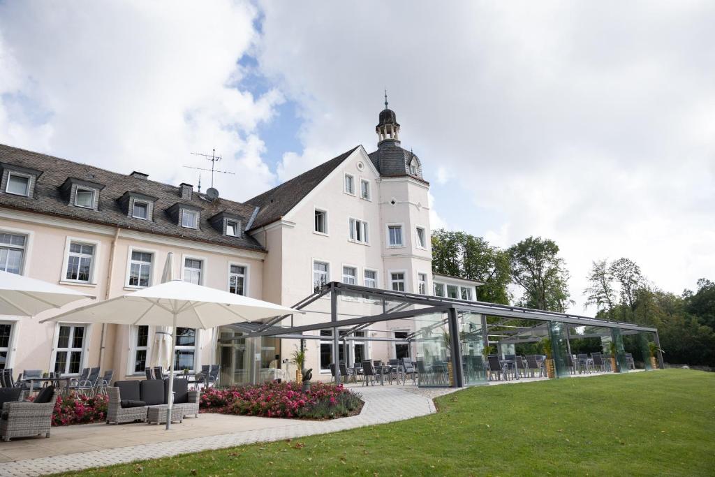 ein großes weißes Gebäude mit einer Terrasse davor in der Unterkunft Hotel Haus Delecke in Möhnesee