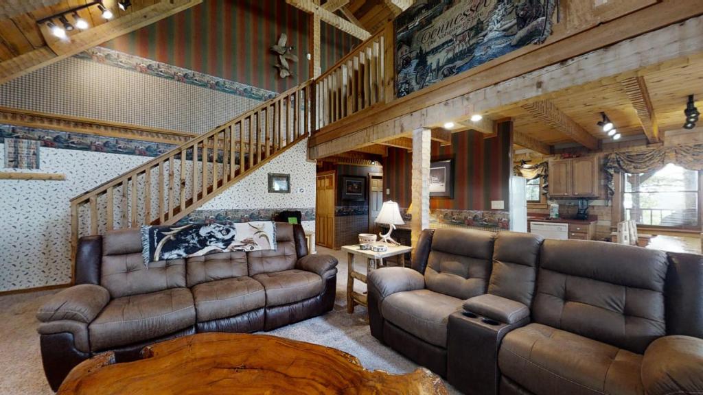 una sala de estar con muebles de cuero y una escalera. en Big Kahuna Lodge, en Sevierville