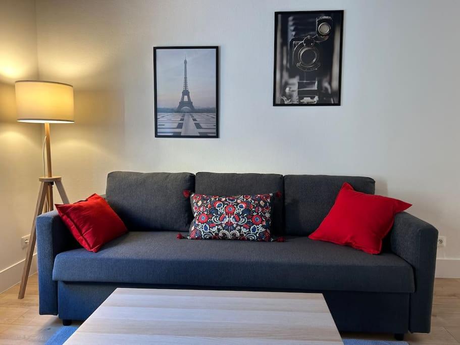 - un canapé bleu avec des oreillers rouges dans le salon dans l'établissement Studio Neuf Hyper Centre St Germain - Proche RER, à Saint-Germain-en-Laye