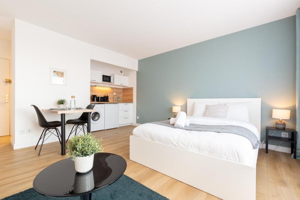 ein weißes Schlafzimmer mit einem weißen Bett und einem Tisch in der Unterkunft Close to the city centre - Appartment confortable in Lille