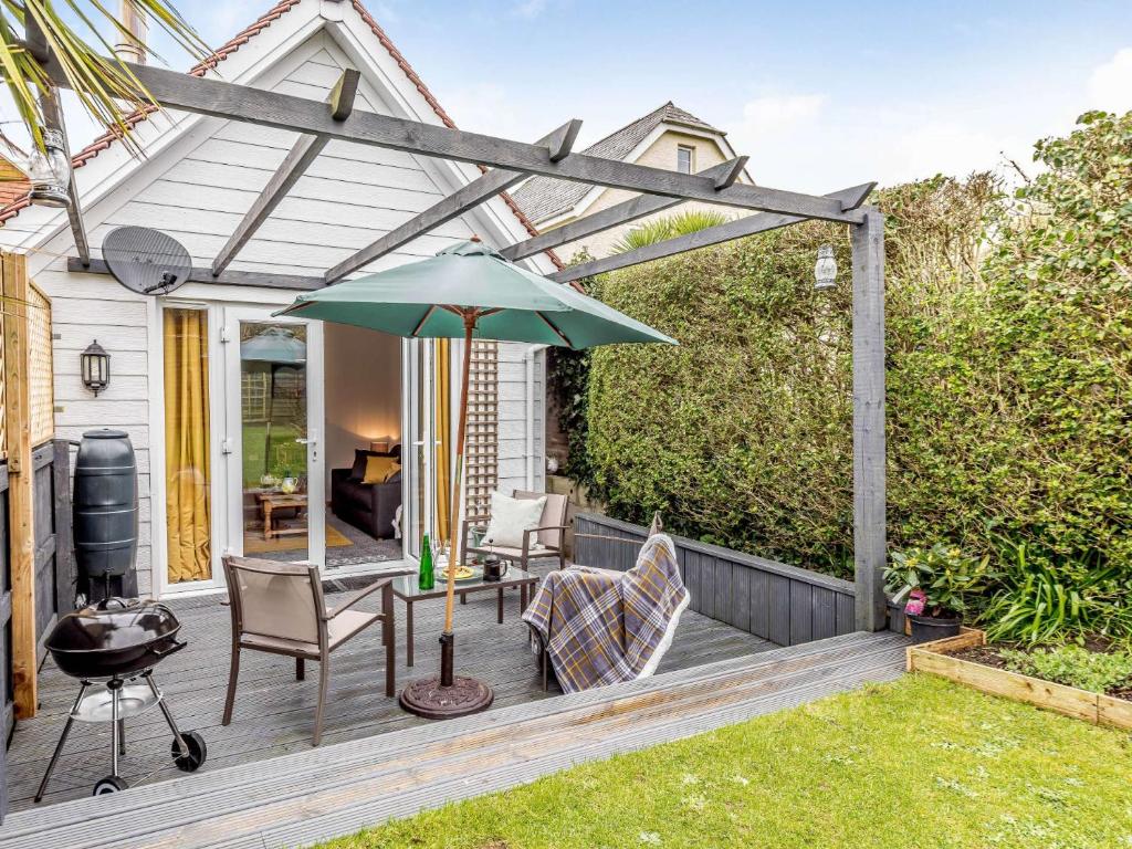 a patio with an umbrella and chairs and a grill at 2 Bed in Bude 82163 in Bude