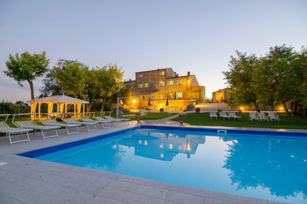 コルトーナにあるVilla Fattoria Le Giareの背景に家があるスイミングプール(椅子付)