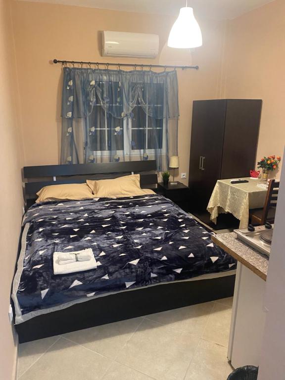 ein Schlafzimmer mit einem Bett mit blauer Decke und einem Fenster in der Unterkunft Dimitris Rooms in Asvestokhórion