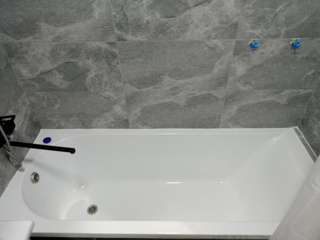 Baño con lavabo blanco y pared de piedra en ЖК Созак. Однокомнатная квартира студия., en Zaozërnyy