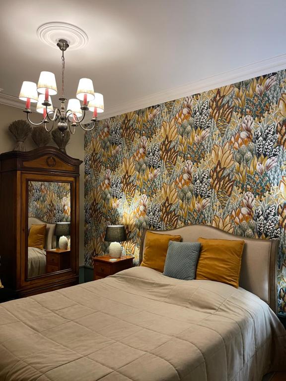 1 dormitorio con 1 cama grande y papel pintado con motivos florales en De la Chambre au Jardin, en Belleville-en-Beaujolais