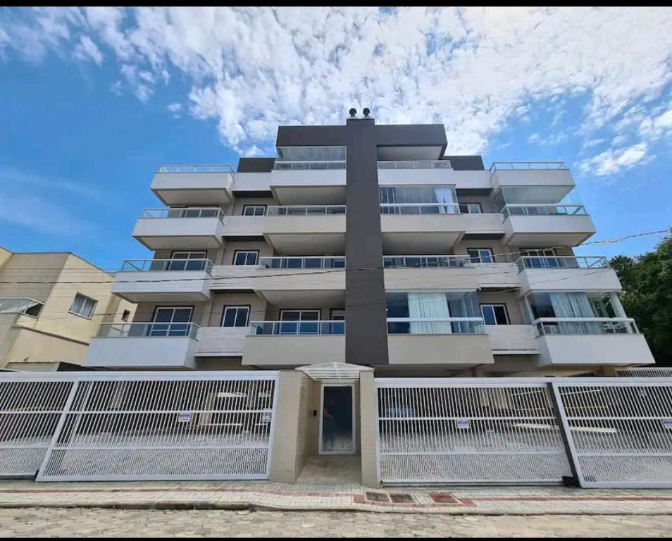 a tall building with a fence in front of it at Apartamento em Bombinhas Próximo ao centro e Passarela do Ribeiro in Bombinhas