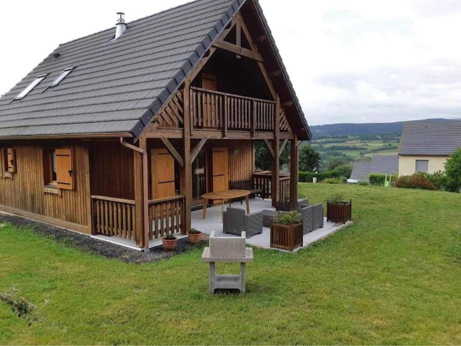 een groot houten huis met een picknicktafel in een veld bij Chalet, Murat (nouveau logement) in Murat