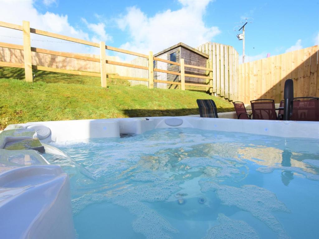a hot tub in a backyard with a wooden fence at 5 bed in Brynteg 75907 in Llanwenog