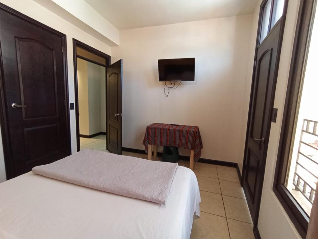 a bedroom with a bed and a table and a television at Hotel Posada Lucia in San Juan La Laguna