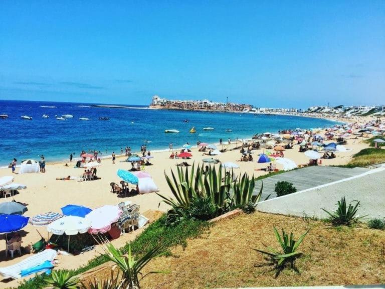 a crowd of people on a beach with umbrellas at Bouznika in Aïn Harrouda