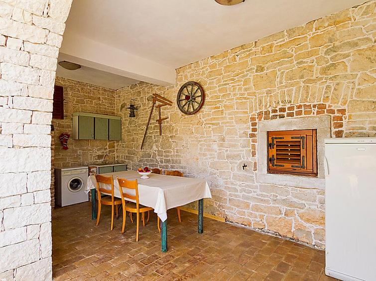 een keuken met een tafel met stoelen en een bakstenen muur bij Villa Zilda in Barat