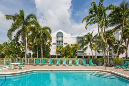 a pool with chairs and palm trees in front of a building at Salt Pond Hideaway 133 by Brightwild in Key West