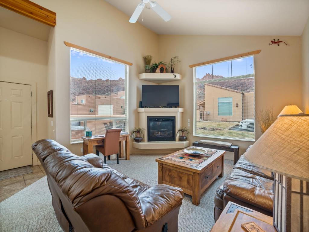 a living room with a leather couch and a fireplace at Rim Village X3 - large patio with private hot tub in Moab