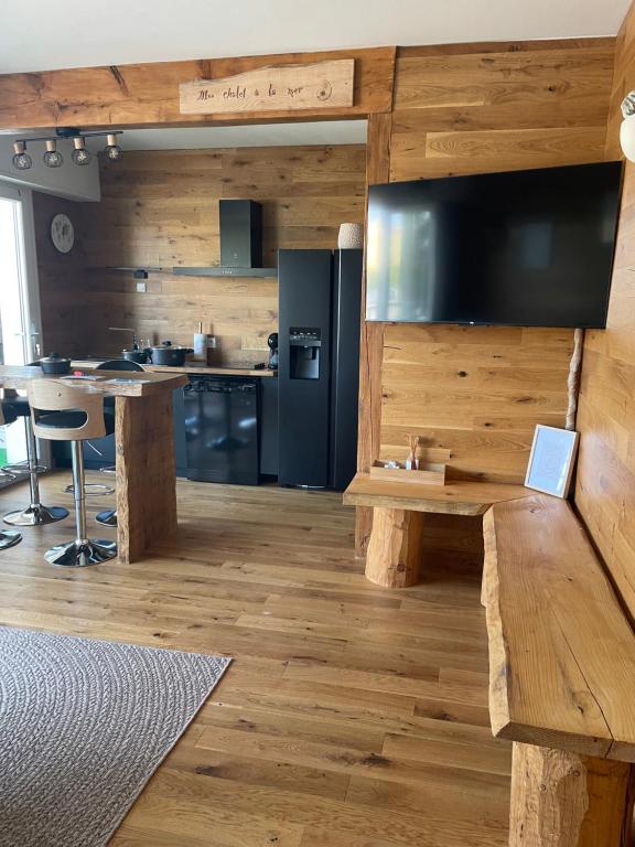 uma cozinha com paredes de madeira e uma mesa com televisão em UN CHALET A LA MER em Saint-Cyprien