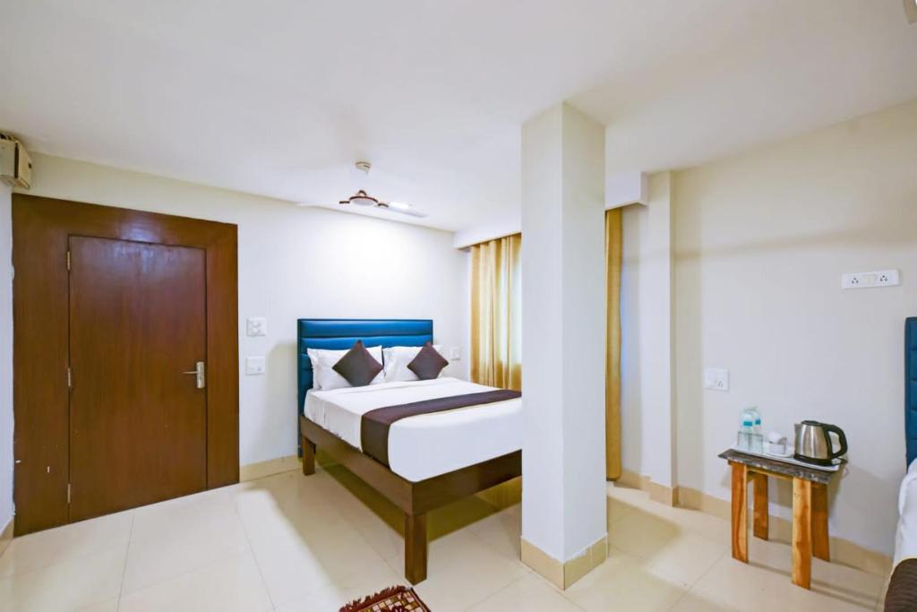 1 dormitorio con 1 cama y puerta de madera en Hotel Amenda Delhi IGI Airport International Mahipalpur, en Nueva Delhi