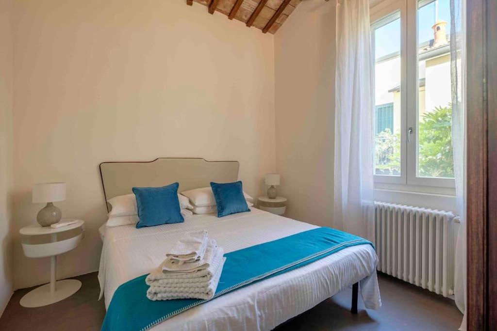 ein Schlafzimmer mit einem Bett mit blauen Kissen und einem Fenster in der Unterkunft La Casetta nel Cerchio in Ravenna
