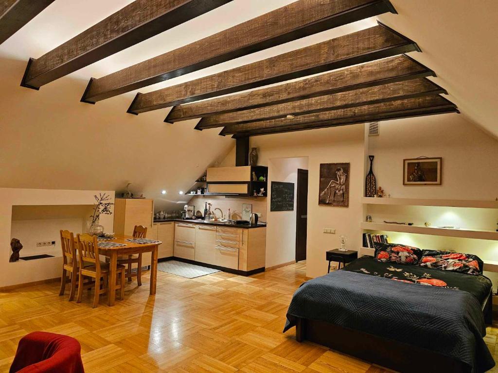 a bedroom with a bed and a table and a kitchen at Jeruzale Park view in Vilnius