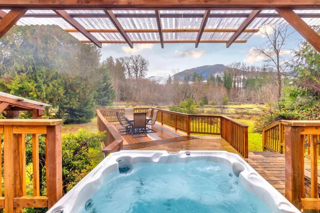 een hot tub op een terras met een pergola bij Waterfront Cabin at White Pass, Mt. Rainier in Packwood