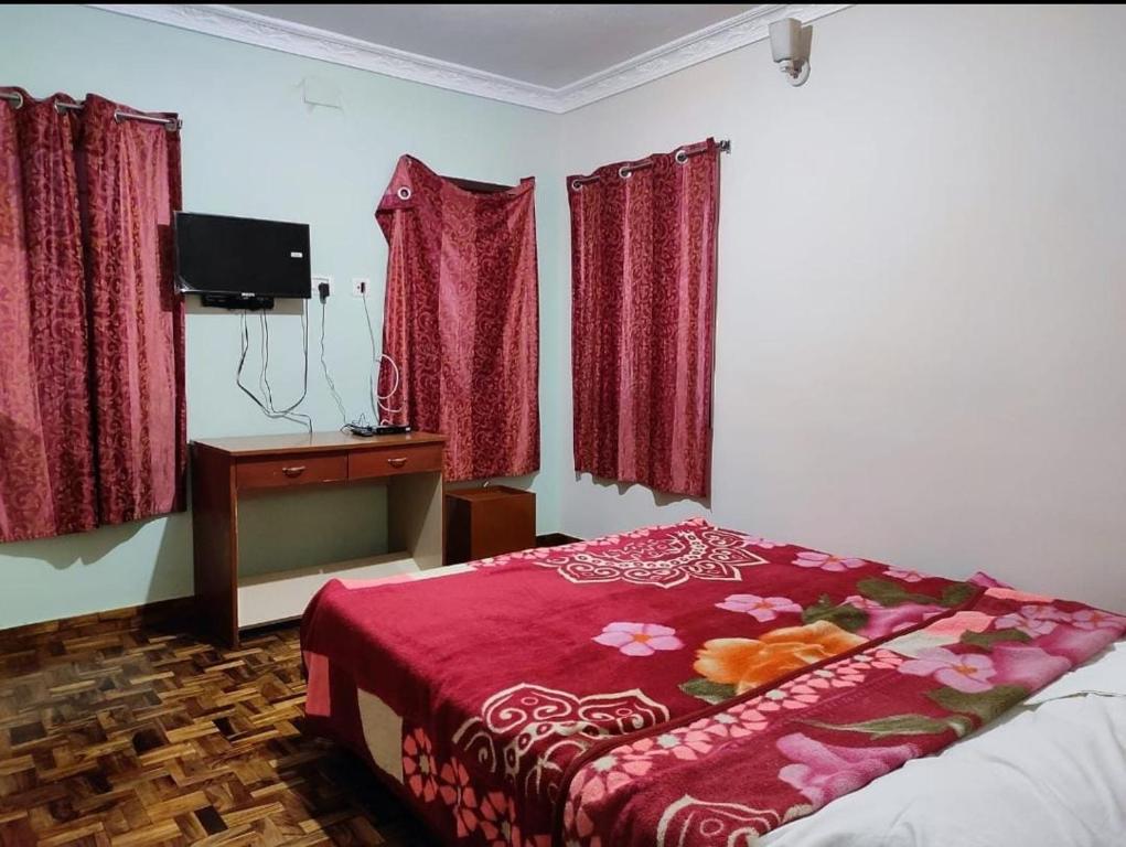 a bedroom with a bed and a dresser and red curtains at Relaxzen Homestay 2 in Kodaikānāl