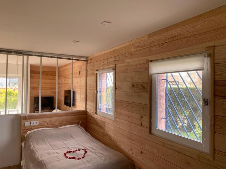 Schlafzimmer mit Holzwänden, einem Bett und einem Fenster in der Unterkunft L’Eden Studio Suite Balneo plein centre d’Andernos in Andernos-les-Bains