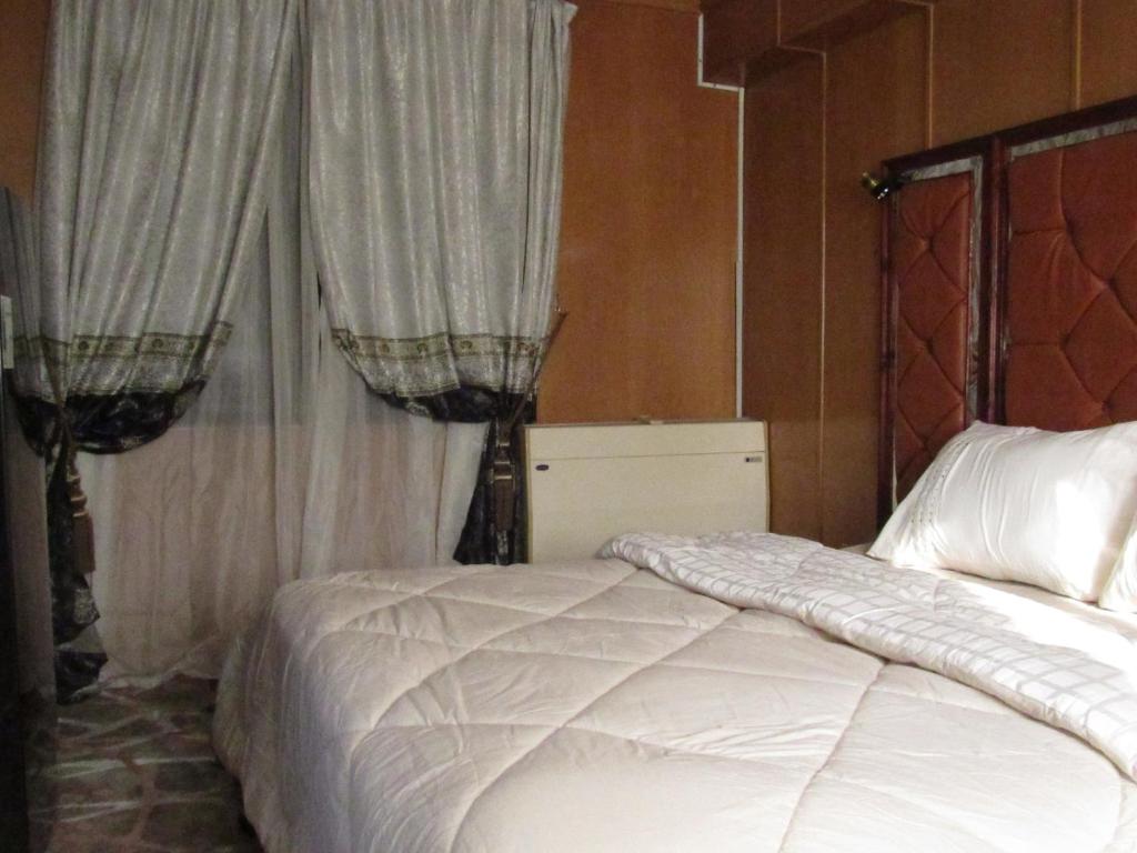 a bedroom with a bed with white sheets and curtains at The guest house in Alexandria