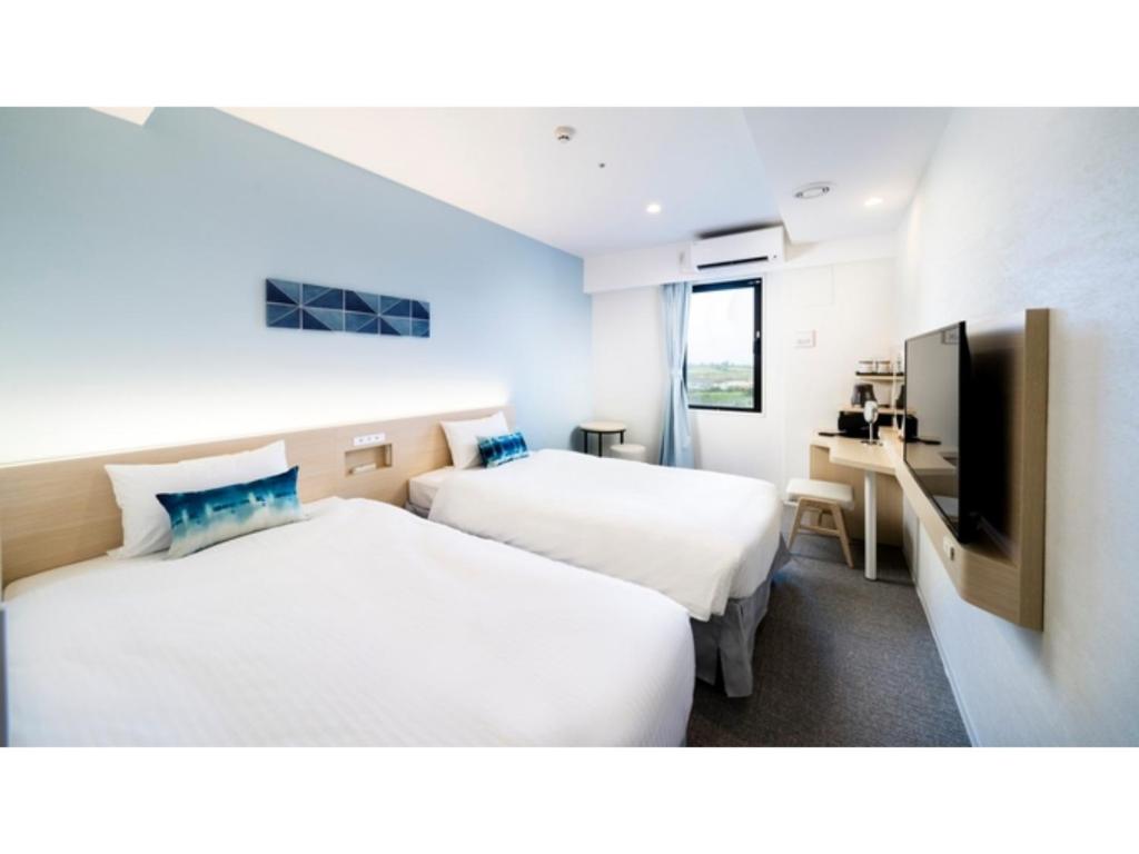 a hotel room with two beds and a tv at Hotel Torifito Miyakojima Resort - Vacation STAY 79479v in Miyako Island
