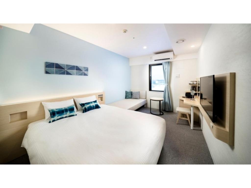 Habitación de hotel con cama y escritorio en Hotel Torifito Miyakojima Resort - Vacation STAY 79474v en Isla Miyako