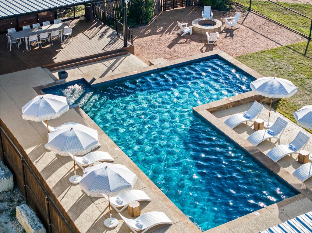 an overhead view of a swimming pool with chairs and umbrellas at Leisure Escape - TX Hill Country in Dripping Springs