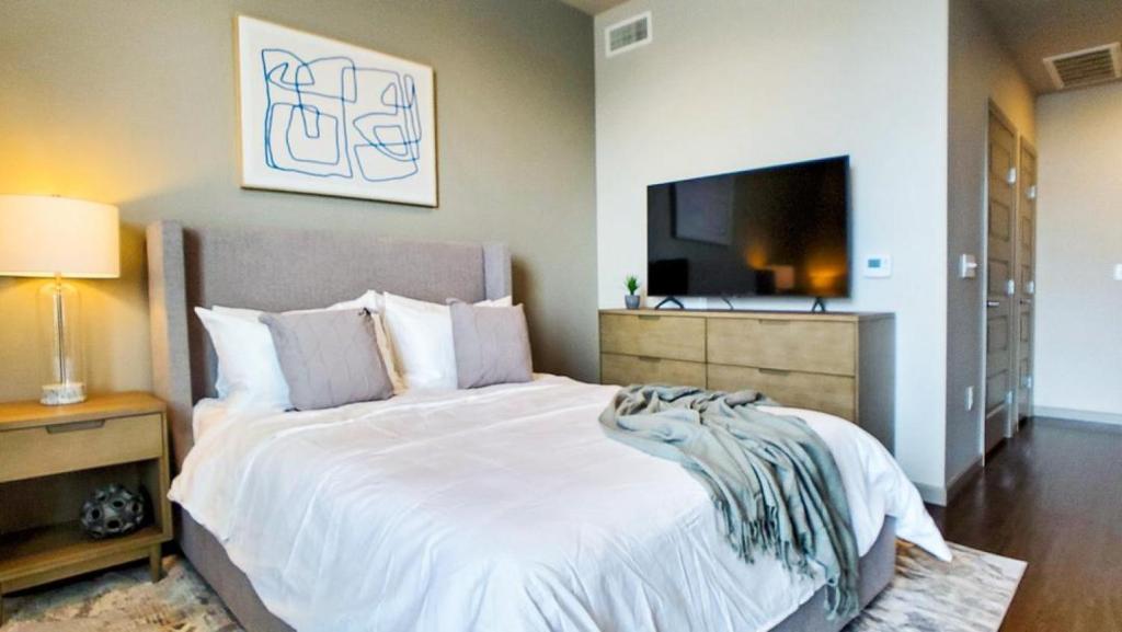 um quarto com uma grande cama branca e uma televisão de ecrã plano em Landing Modern Apartment with Amazing Amenities (ID3107X26) em Denver