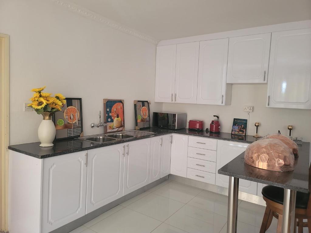 a kitchen with white cabinets and a vase of flowers on the counter at Royal Eagles in Gaborone