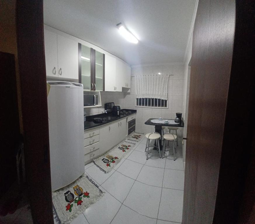 a kitchen with a refrigerator and a table in it at Estadia da Josi in Balneário Camboriú