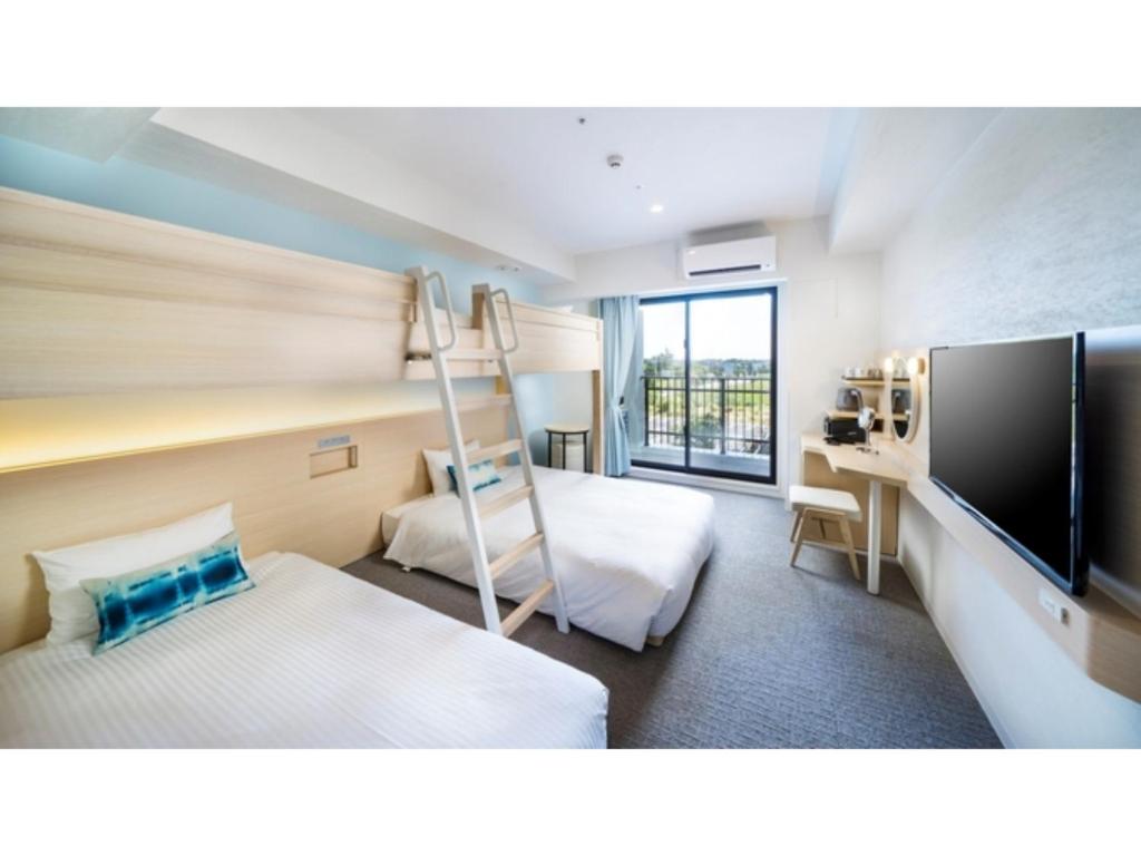 Hotel Torifito Miyakojima Resort - Vacation STAY 79486v في جزيرة مياكو: غرفة في الفندق سرير بطابقين وتلفزيون