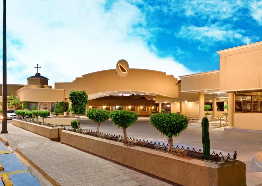 une église avec des arbres devant un bâtiment dans l'établissement Hotel San Angel, à Hermosillo