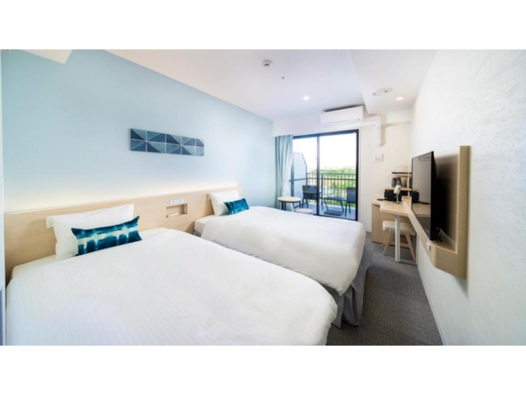 una camera d'albergo con due letti e una televisione di Hotel Torifito Miyakojima Resort - Vacation STAY 79490v a Miyakojima