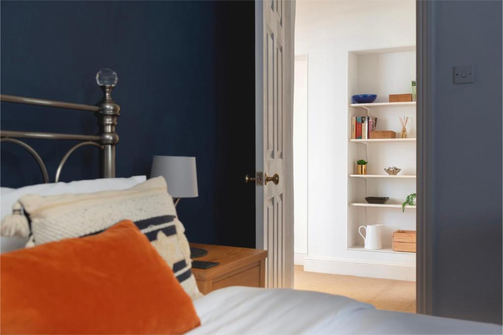a bedroom with blue walls and a bed with an orange pillow at Parade Watch in Bath