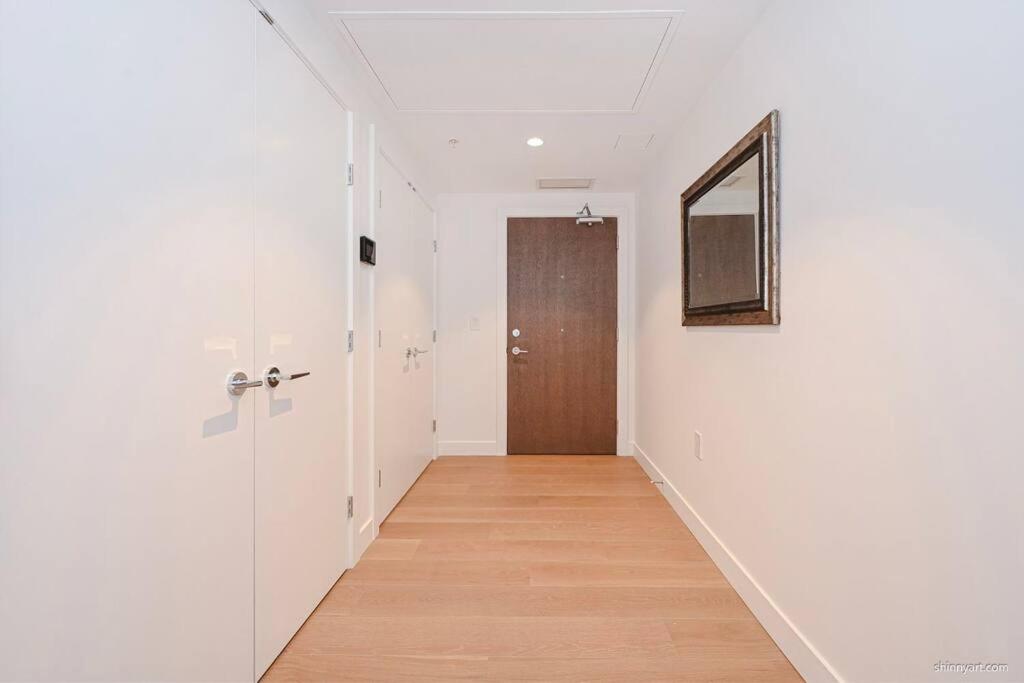 a hallway with white walls and a mirror and a door at new apartment 3 bedrooms in Richmond