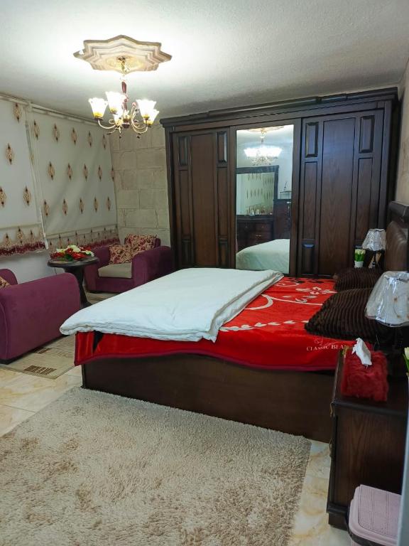 - une chambre avec un grand lit et une couverture rouge dans l'établissement White tulips apartment الزنبقة البيضاء, à Jerash