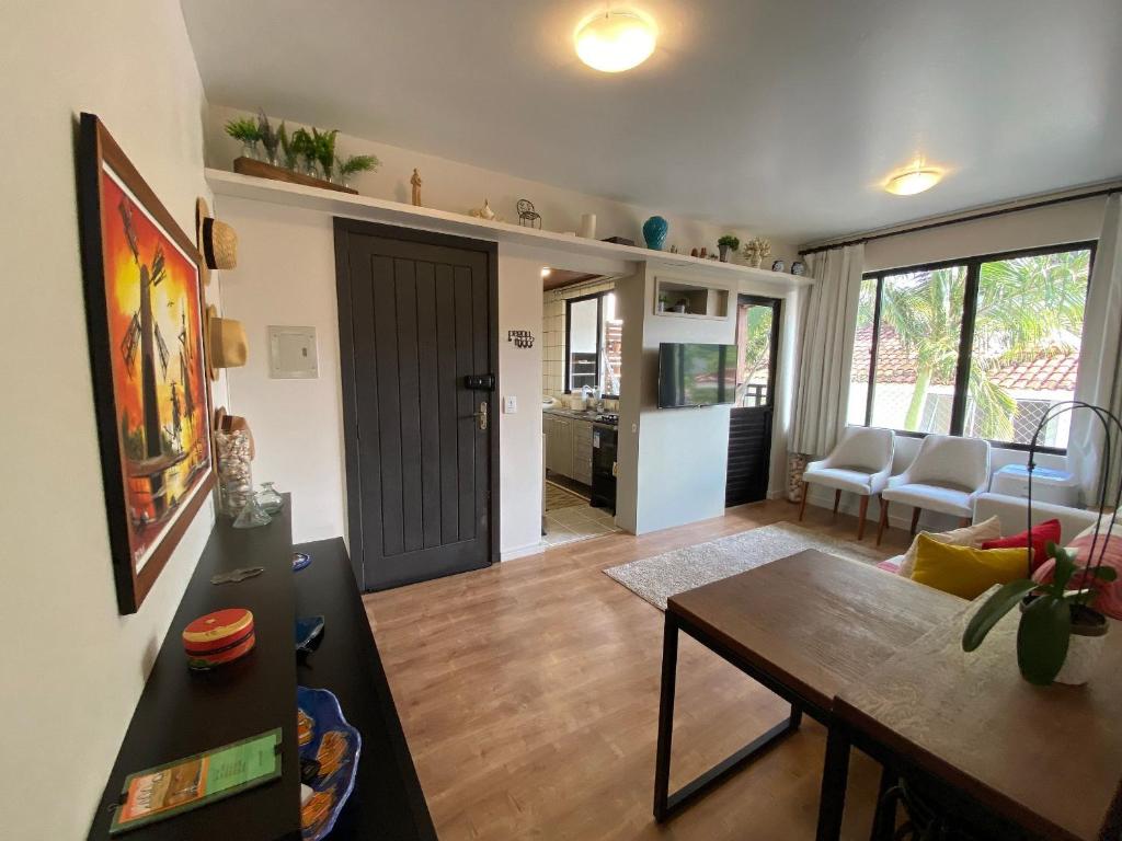 Una sala de estar con una mesa y un comedor. en Apto tranquilo a 3min da praia Canasvieiras FML202, en Florianópolis