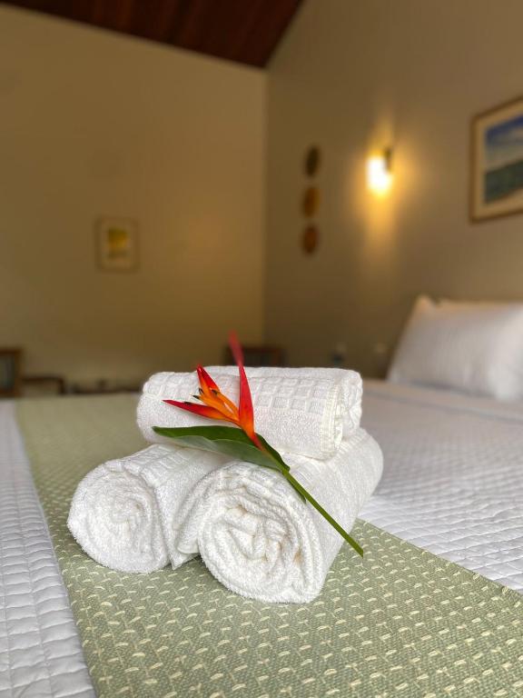 a pile of towels and a flower on a bed at Pousada Mãe Natureza in Pirenópolis