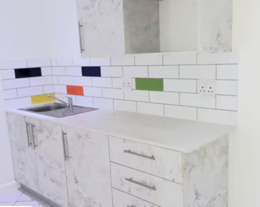 eine weiße Küche mit einem Waschbecken und einem Spiegel in der Unterkunft Cavendish Suite Bachelor in Kapstadt