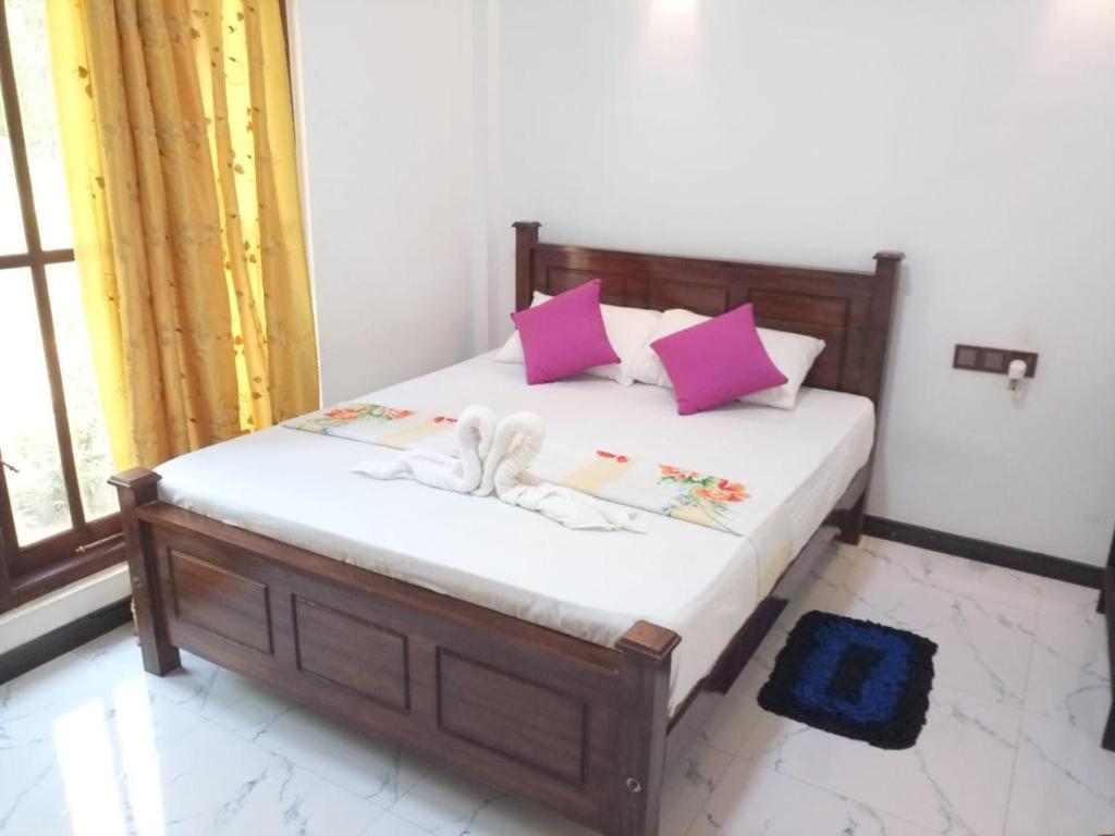 a bedroom with a bed with pink and white pillows at Silent Peacock Villa And Peacock Cafe in Tangalle