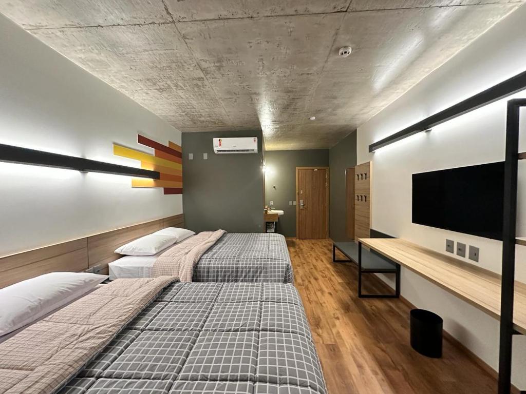 Duas camas num quarto com uma televisão de ecrã plano em Hotel 10 Sorriso em Sorriso