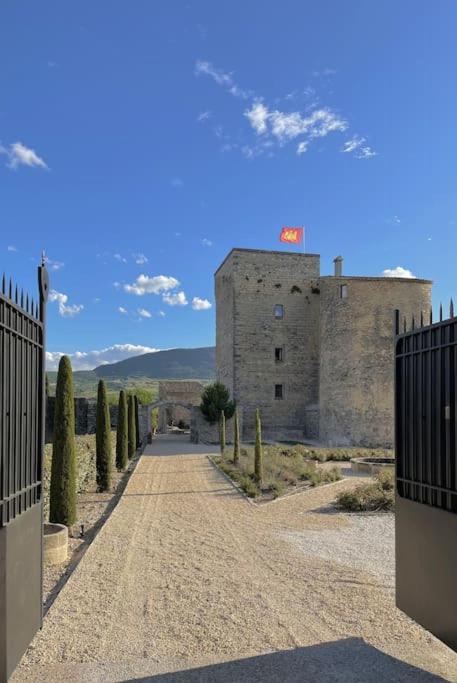 un chemin de terre devant un bâtiment arboré dans l'établissement Château de Sainte Jalle, à Sainte-Jalle