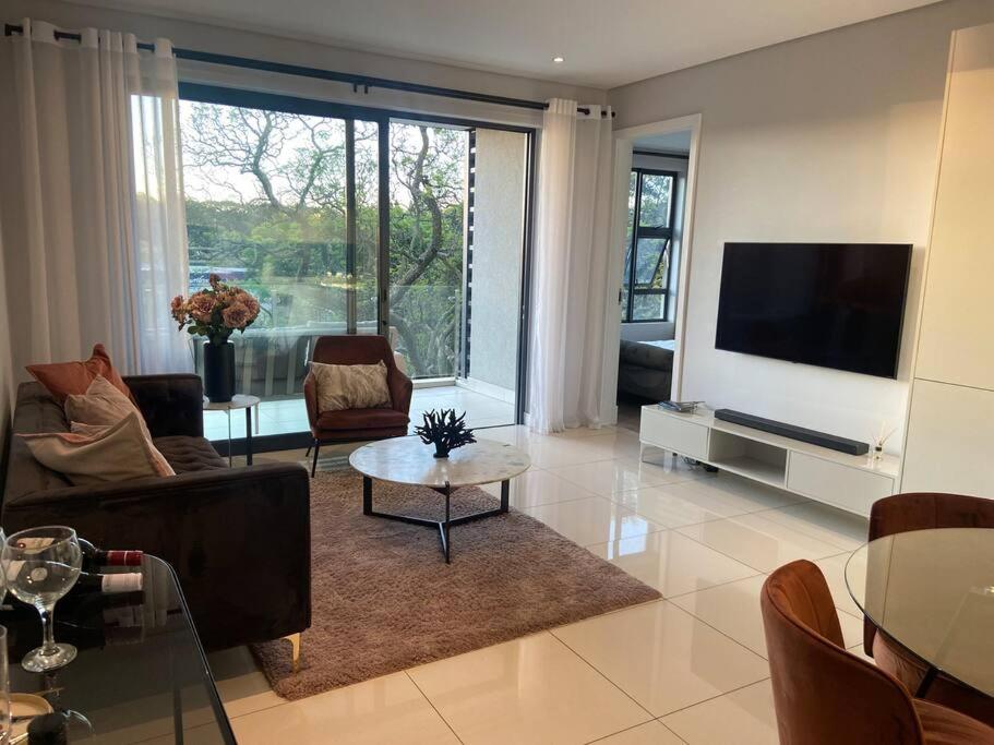 a living room with a couch and a tv and a table at Load-Shedding Free Trendy 2-bed 2-bath Apartment in Johannesburg