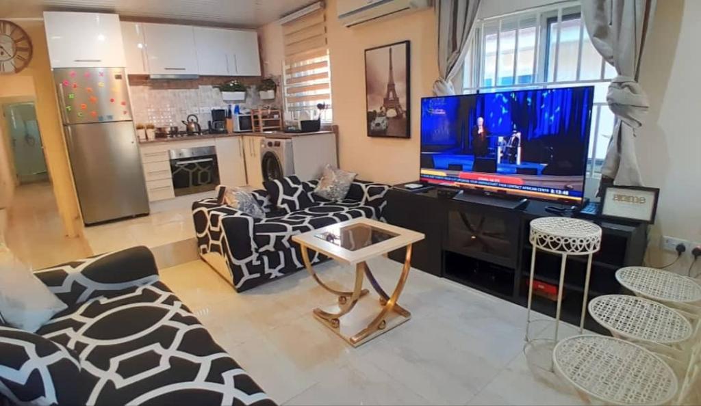 a living room with a television and a couch and chairs at Bienvenue in Accra