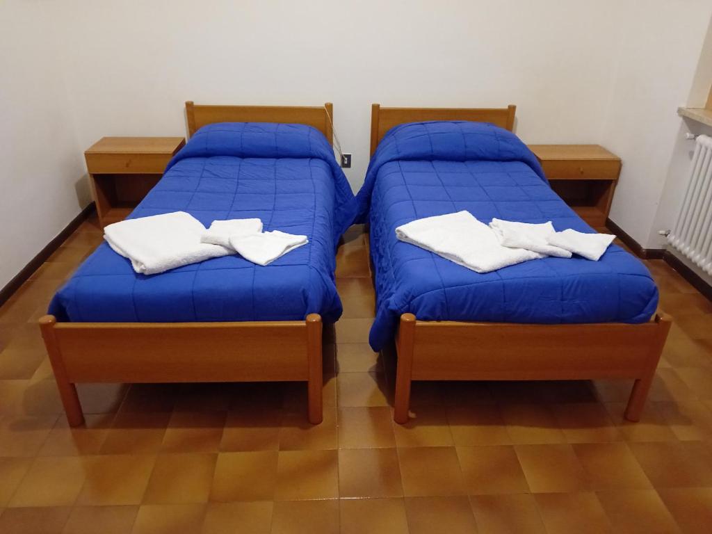 2 camas en una habitación con sábanas azules y toallas blancas en Casa vacanze Monica en Campodenno
